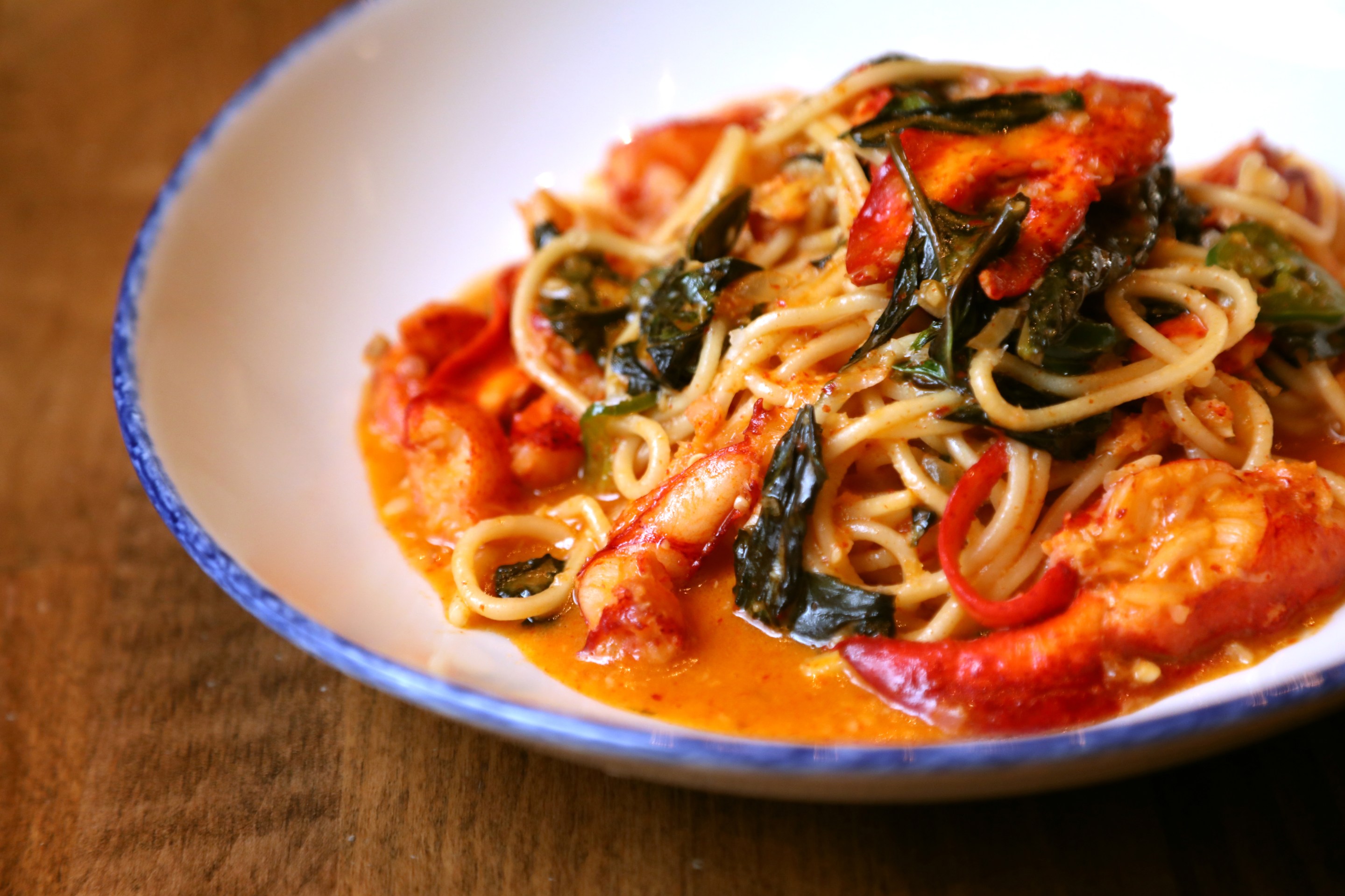 Lobster pasta with spaghetti and basil in a tomato-based sauce.