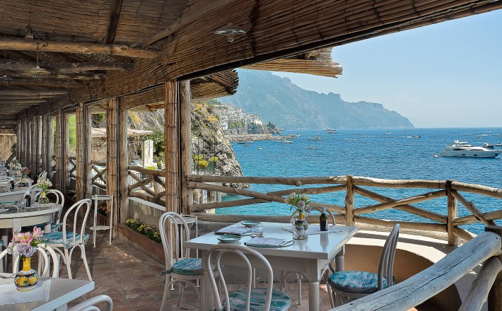 View of the Mediterranean from patio with white tables and chairs, table set.