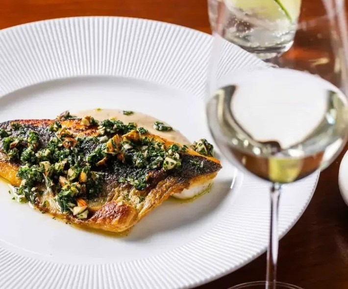 A seared branzino fillet topped with herb and almond gremolata, served at Casa Bianca in Austin.
