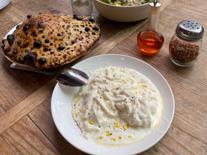 Plate of stracciatella cheese with olive oil, paired with rustic bread