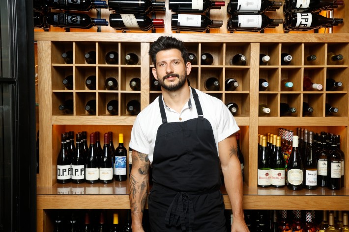 Chef Giorgio Rapicavoli standing in front of a wine wall.