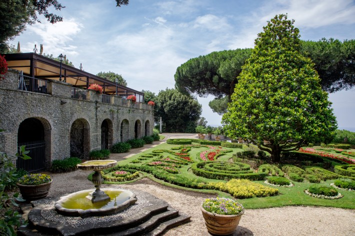 Formal gardens with fountain and stone terrace at Borgo Laudato Si’ in Vatican City.