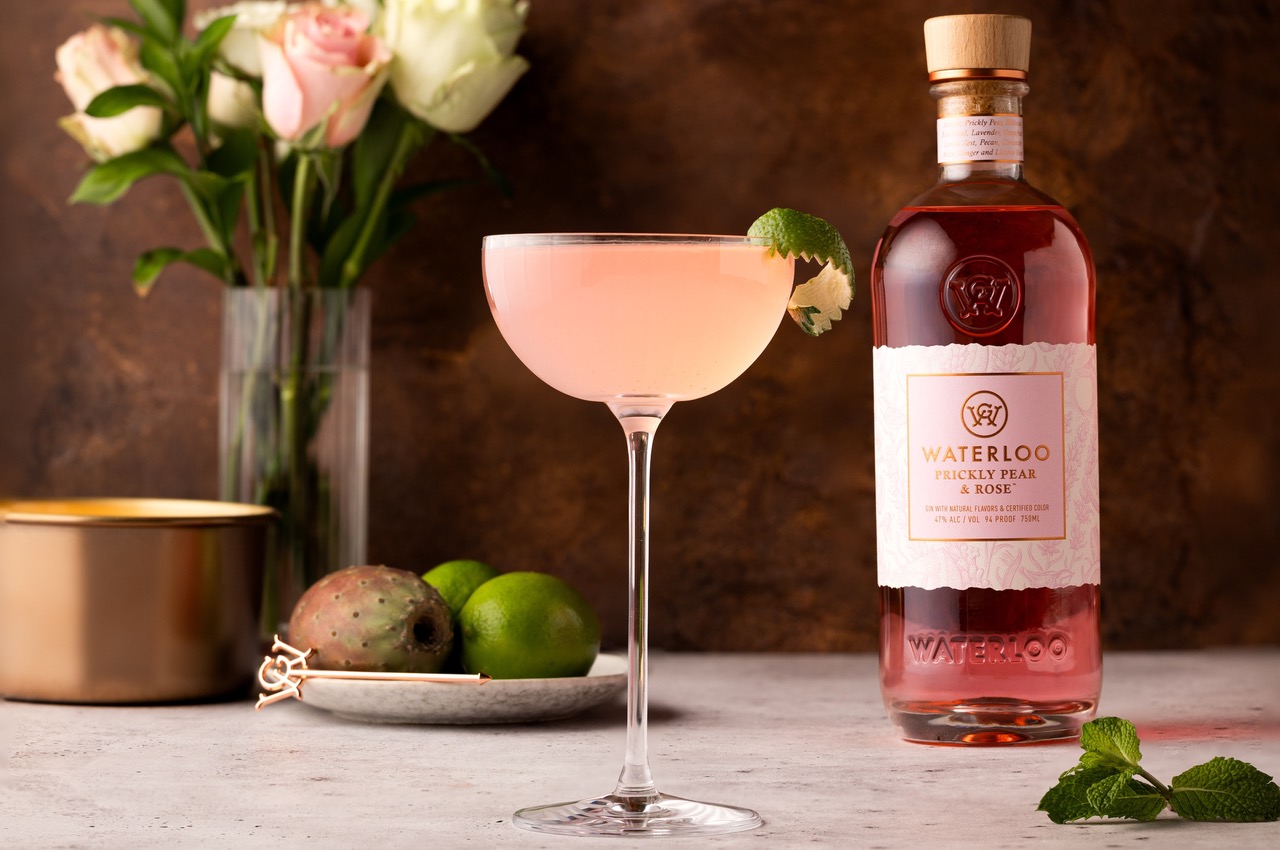 Bottle of Waterloo Prickly Pear and Rose White Gin next to a pink cocktail.
