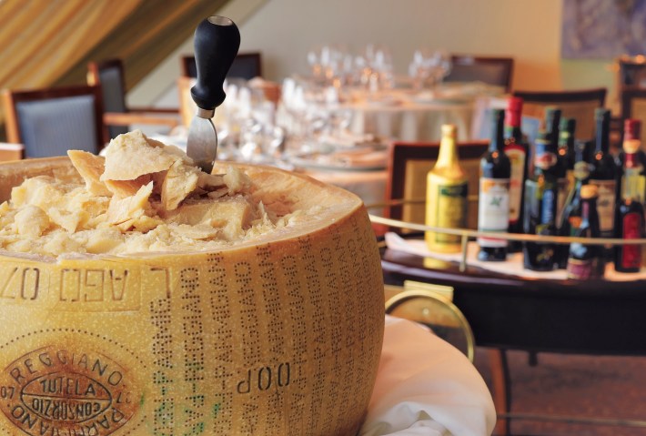 A large wheel of Parmigiano-Reggiano at Toscana on Oceania’s Allura, surrounded by bottles of olive oil