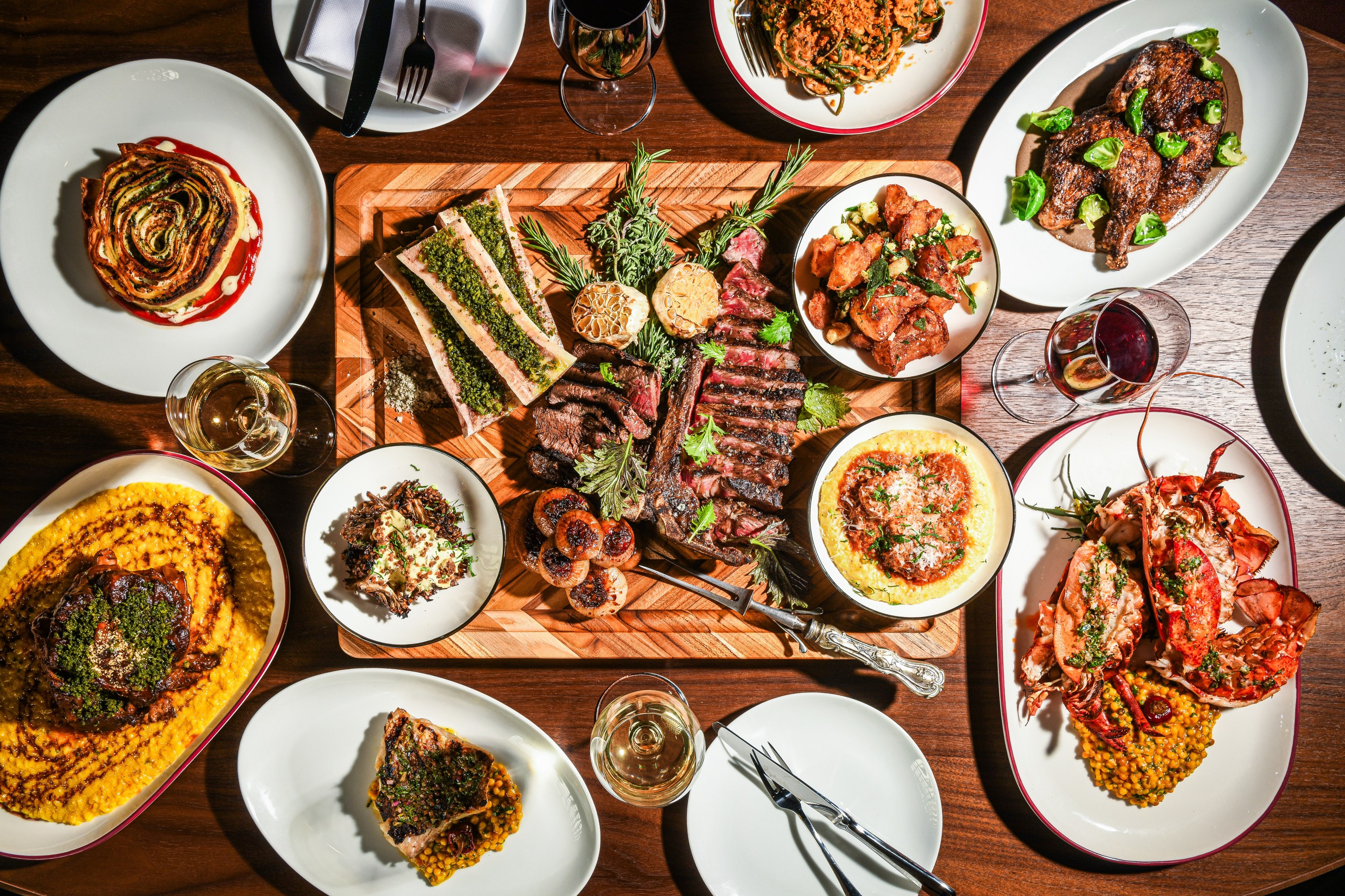 A table filled with steak, lobster, pasta, and risotto at Acqua Bistecca.