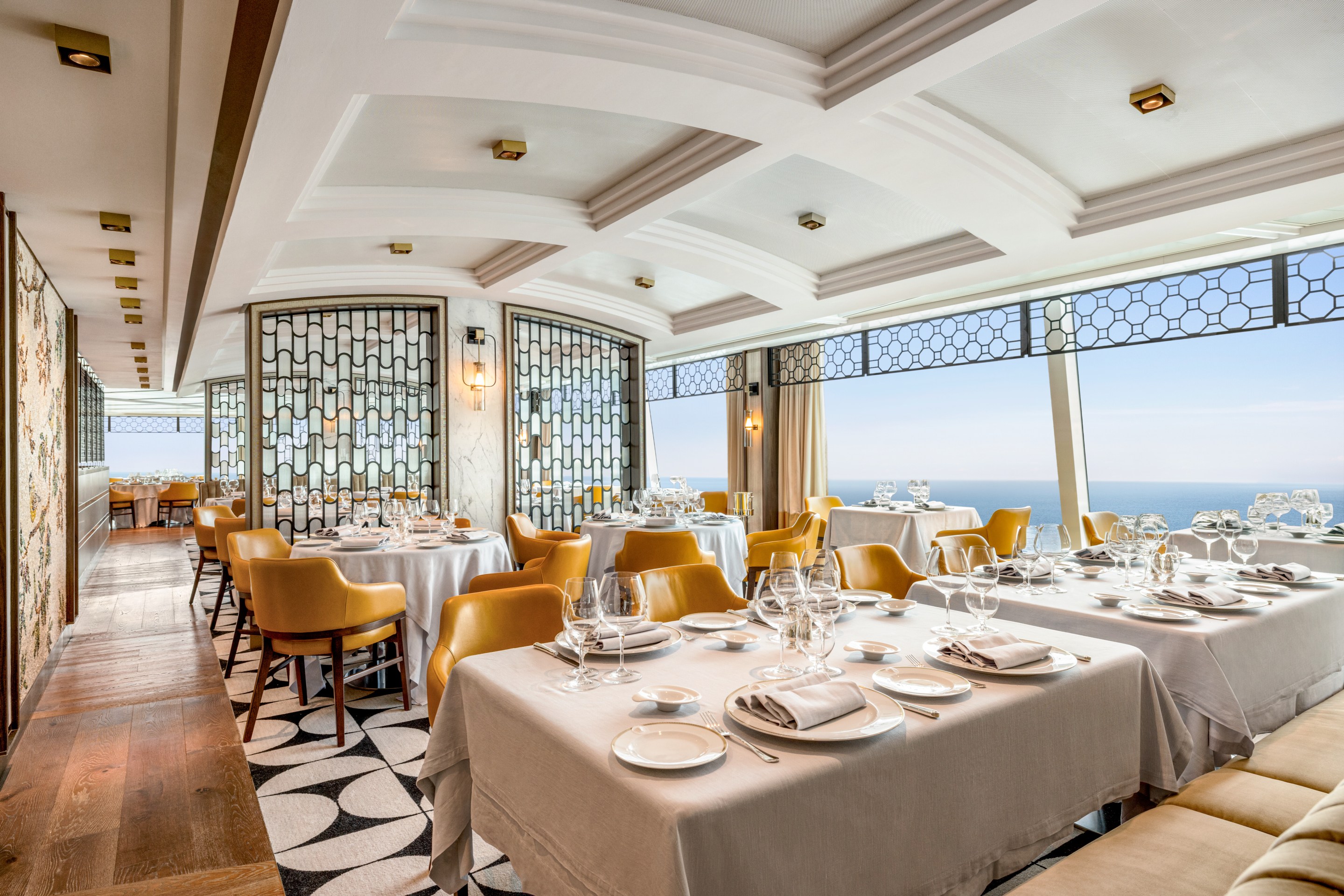Elegant dining room of Toscana on Oceania’s Allura with ocean views and gold-toned chairs