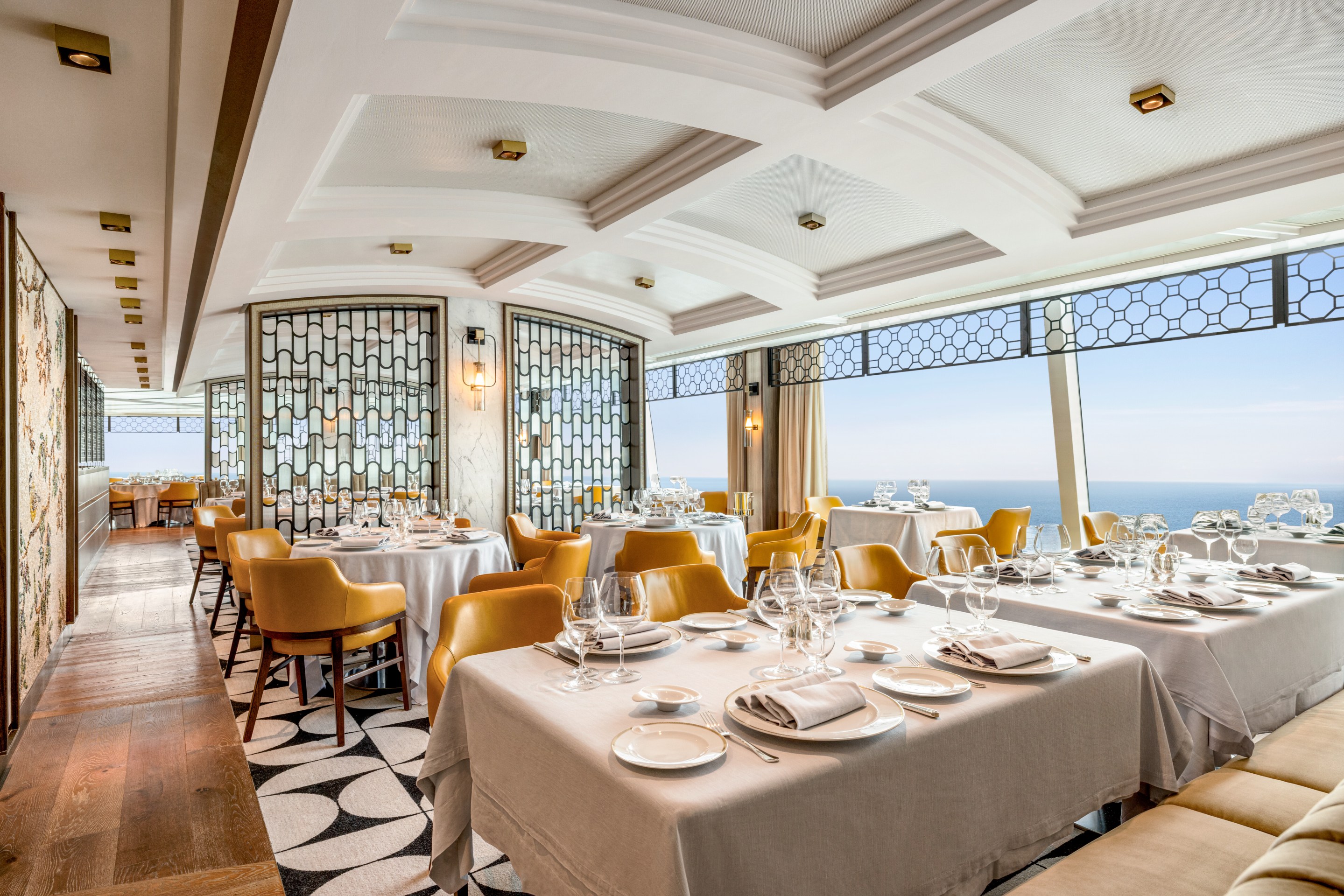 Elegant dining room of Toscana on Oceania’s Allura with ocean views and gold-toned chairs