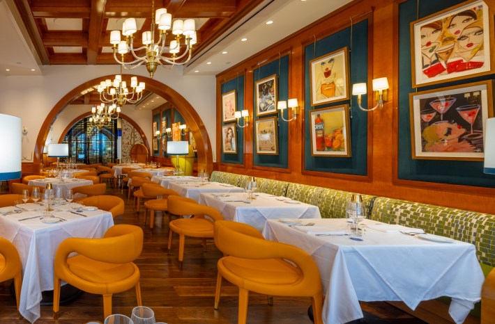 Dining room at Tutti Bene Bozeman with orange chairs and colorful artwork