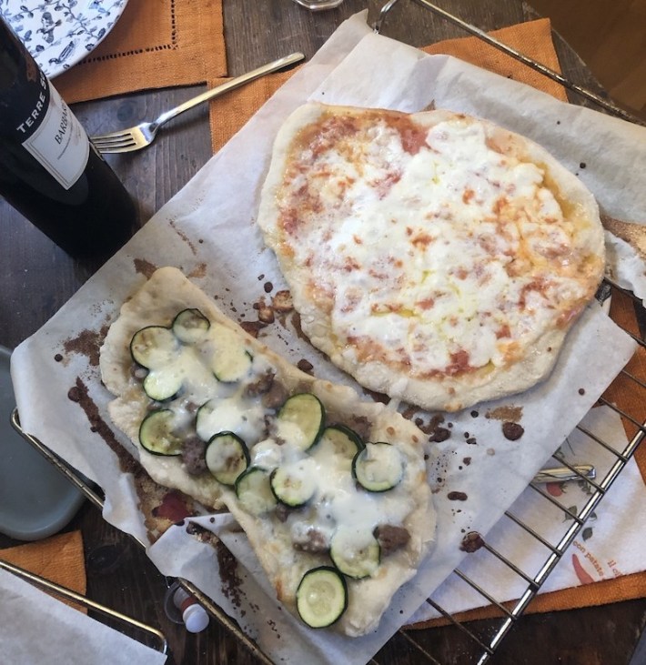 One round and one rectangular pizza, fresh out of the oven with melted cheese.