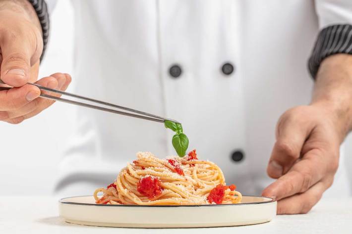 Close-up of chef plating spaghetti with basil at Tutti Bene Bozeman.