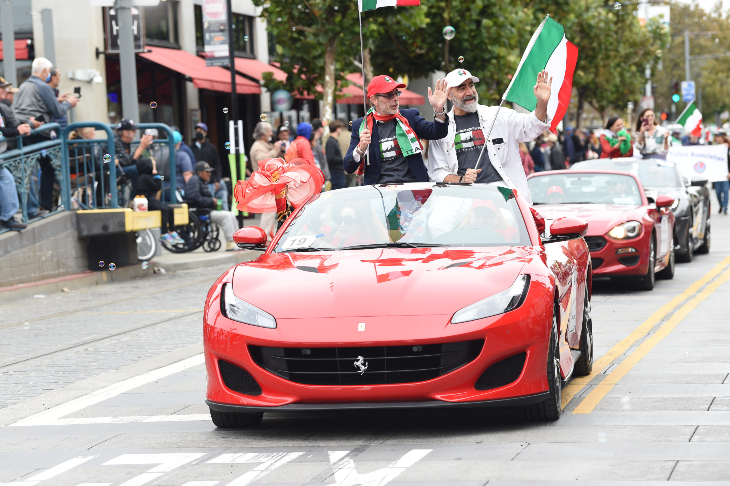 Crowds and fancy cars with Italian flags during the San Francisco Italian Heritage Parade in North Beach.
