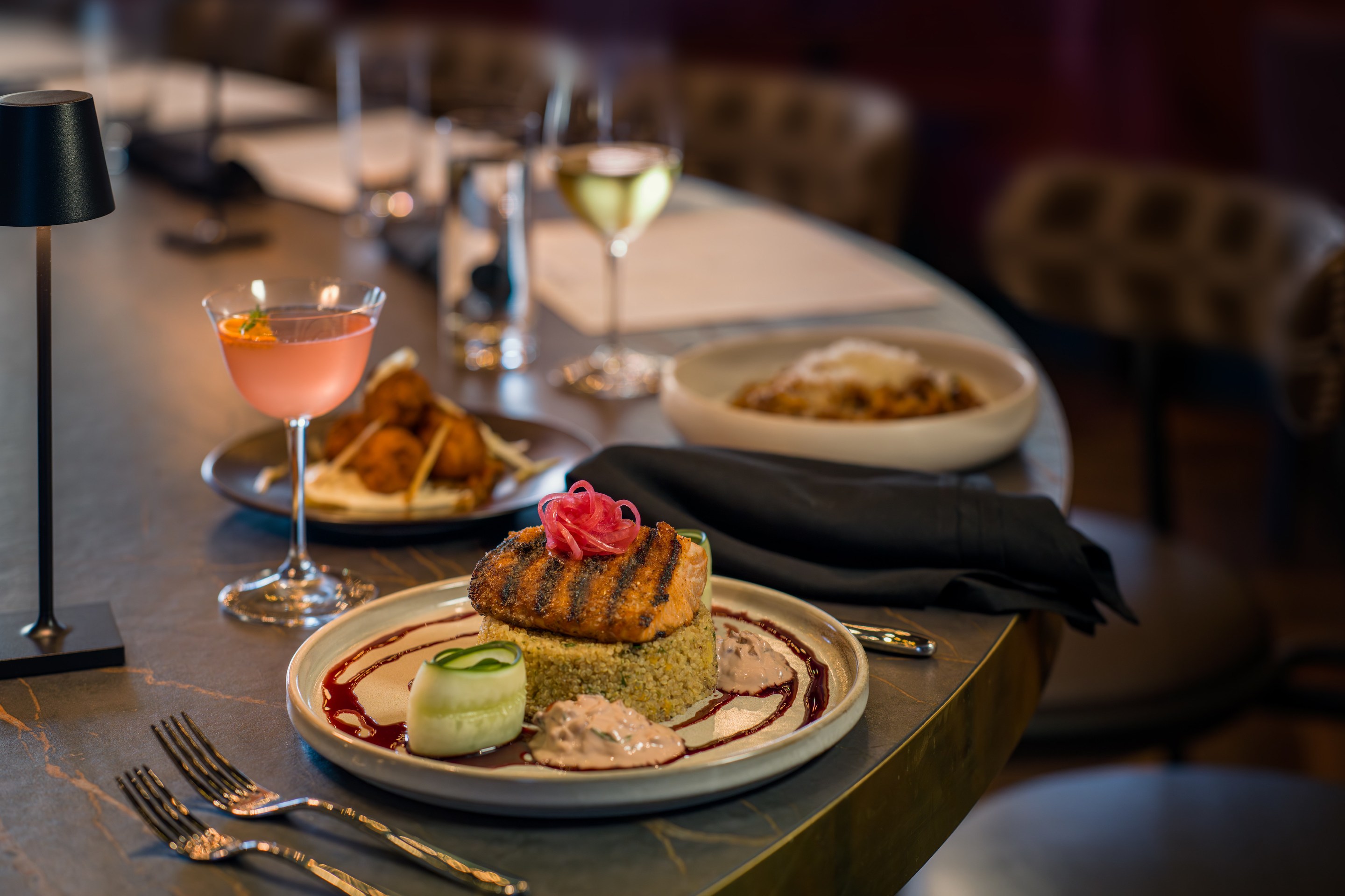 Salmon topped with pickled onions, plated with a cocktail.