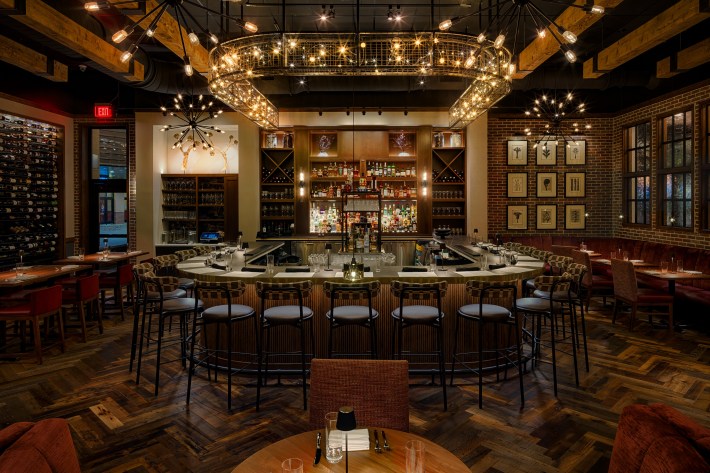 Dining room and bar at Posana in Biltmore Park, lit up with chandeliers.