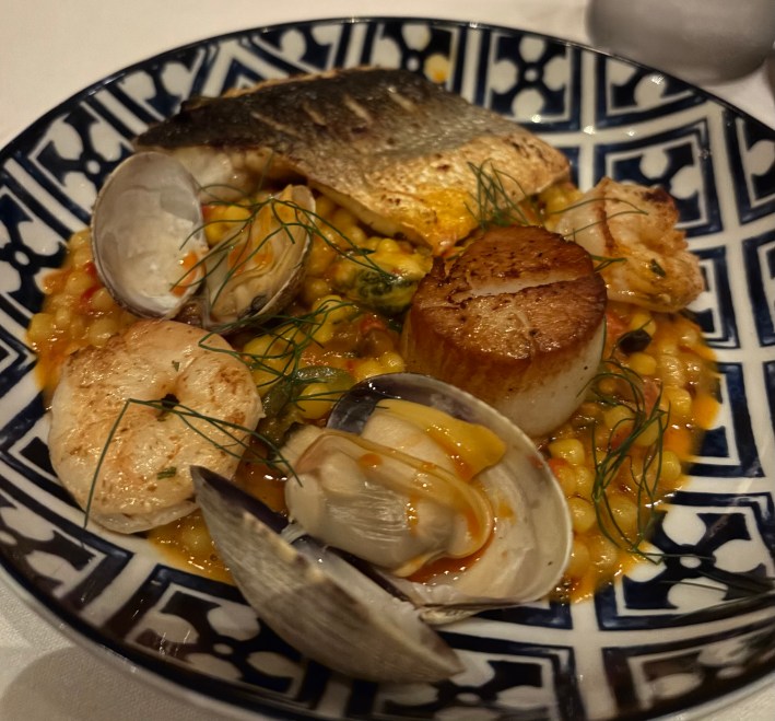 Bowl of seafood risotto with scallops, clams, and fish served in a patterned blue dish at Il Caminetto Whistler.