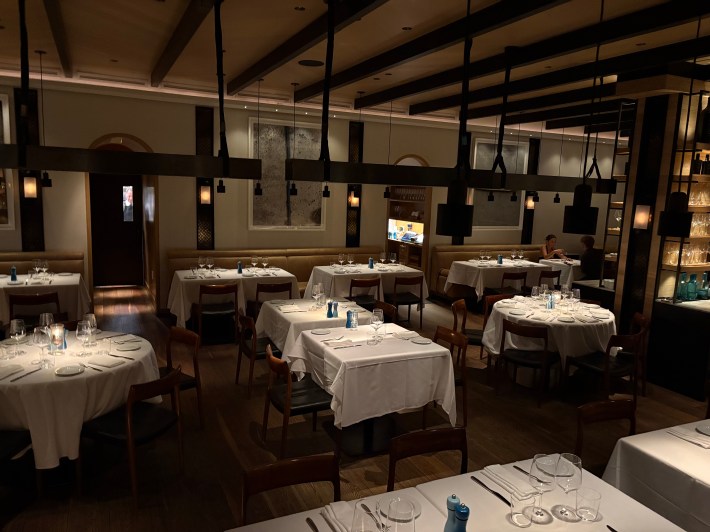 Interior of Il Caminetto restaurant in Whistler with white tablecloths and softly lit dining area.