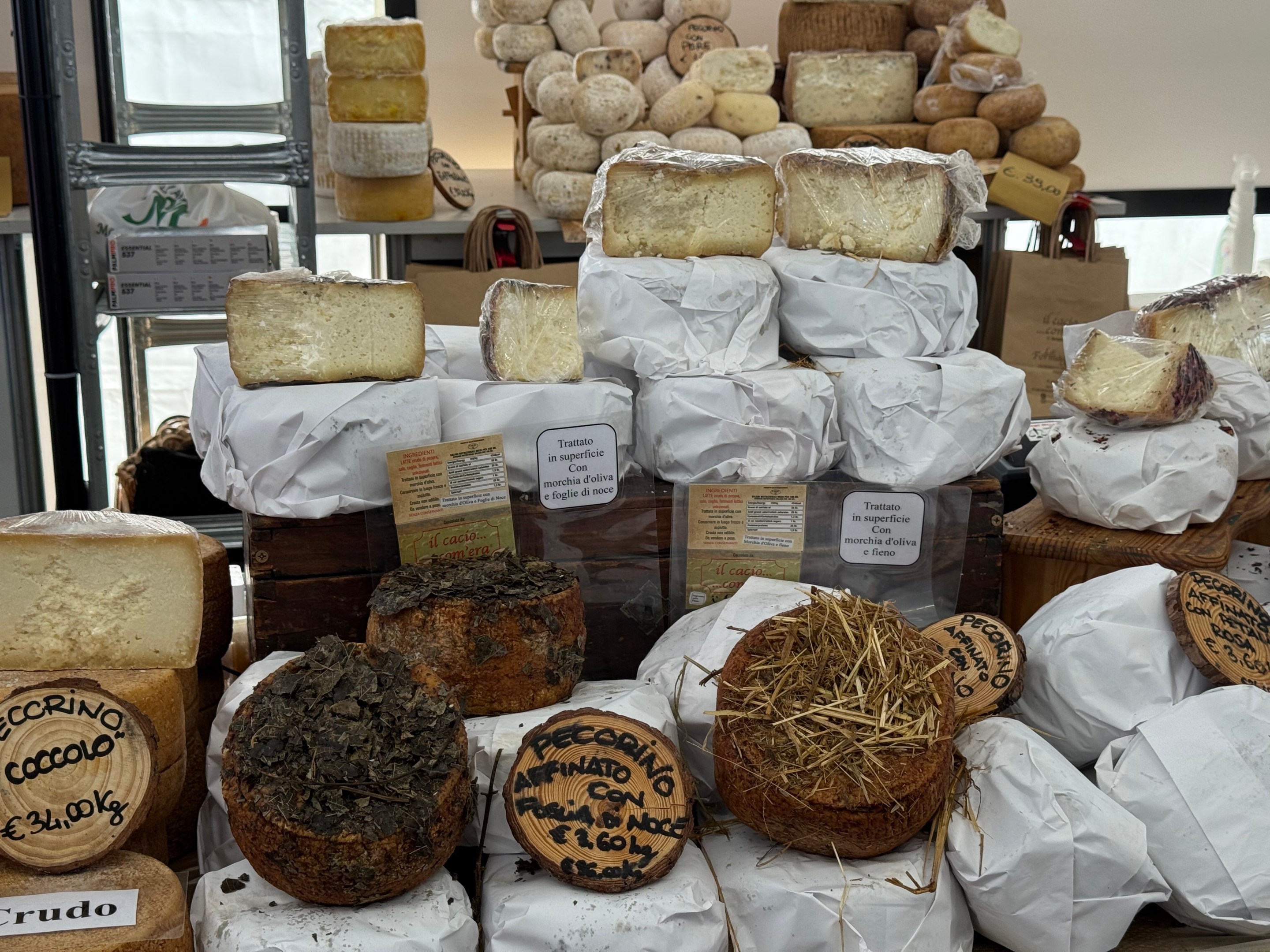 A colorful cheese stall with wheels of raw milk cheese and traditional dairy tools in Bra.