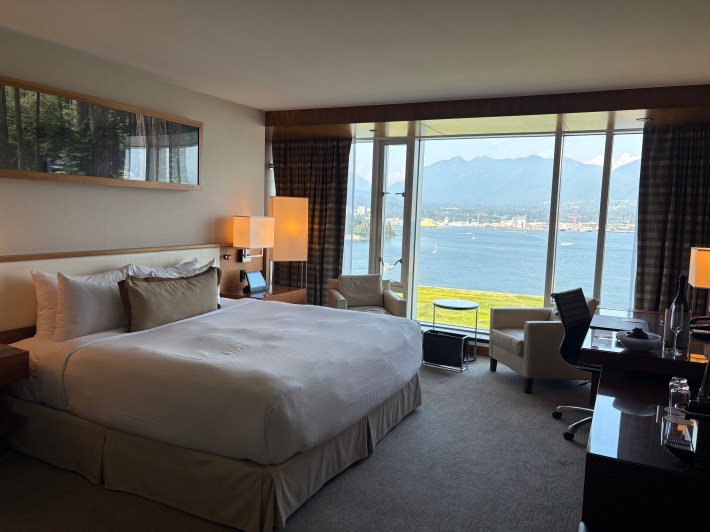 Luxury guest room at Fairmont Pacific Rim with large window view of Vancouver Bay and surrounding mountains.
