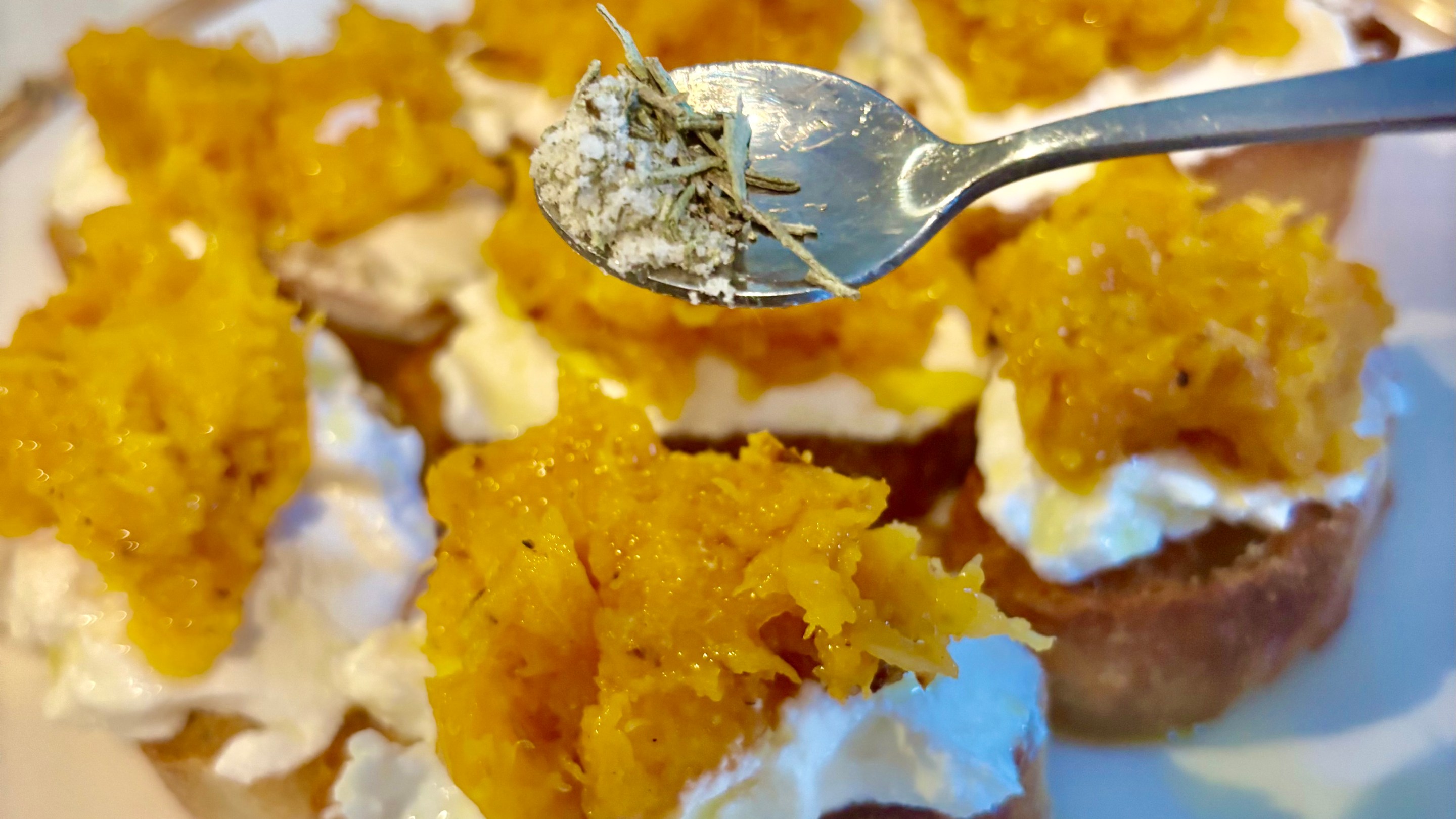 Autumn bruschetta topped with ricotta and roasted butternut squash with rosemary salt being sprinkled