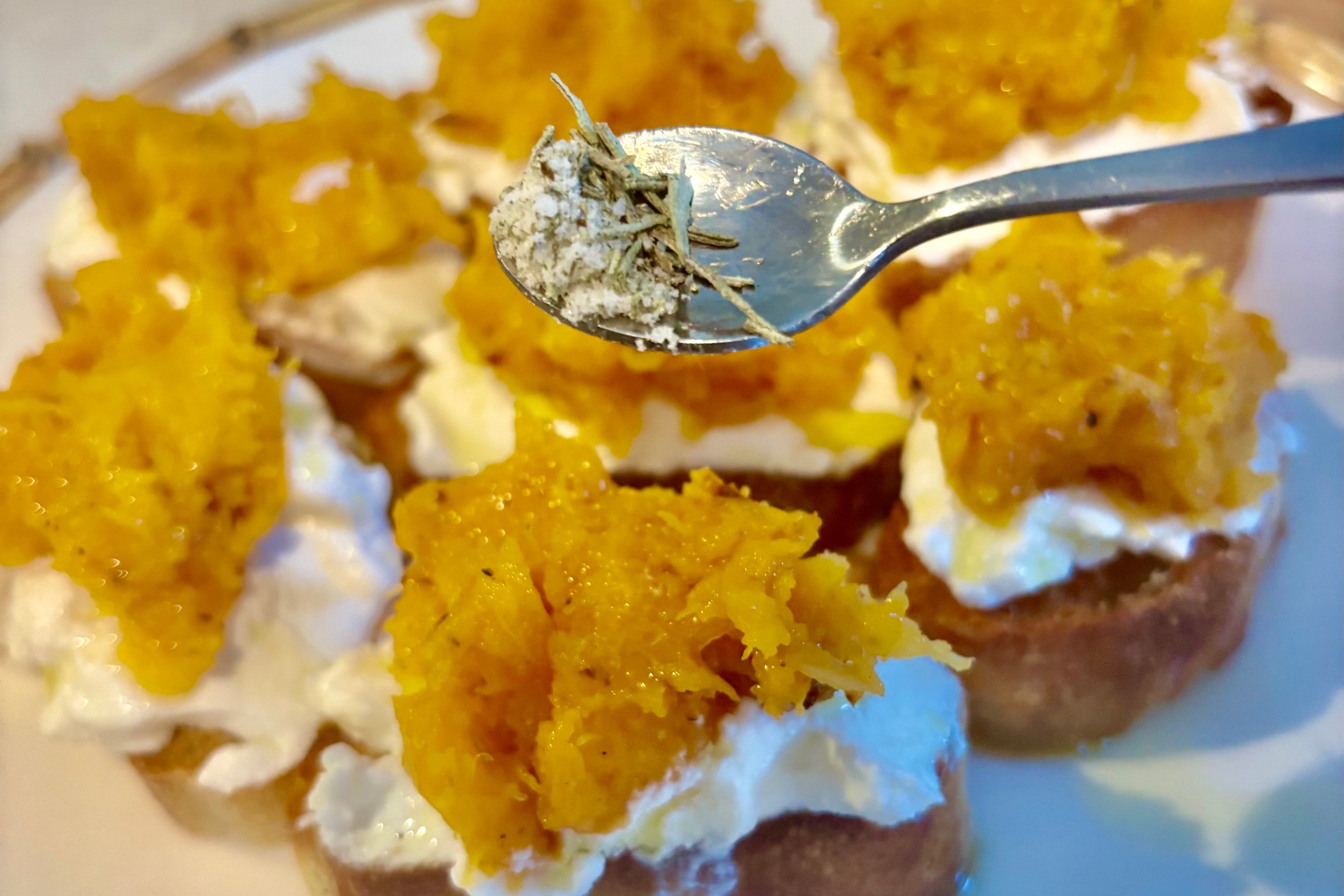 Autumn bruschetta topped with ricotta and roasted butternut squash with rosemary salt being sprinkled