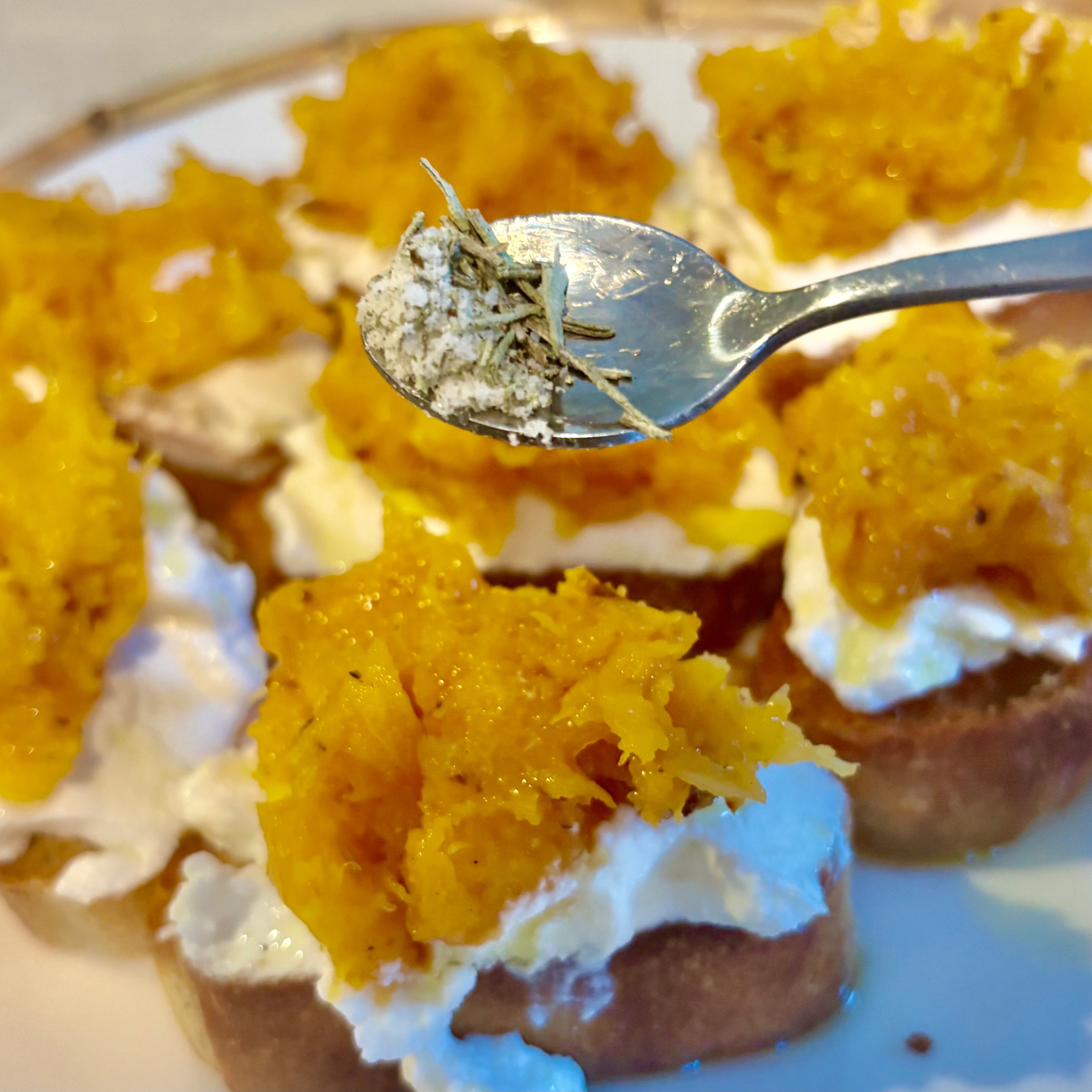 Autumn bruschetta topped with ricotta and roasted butternut squash with rosemary salt being sprinkled