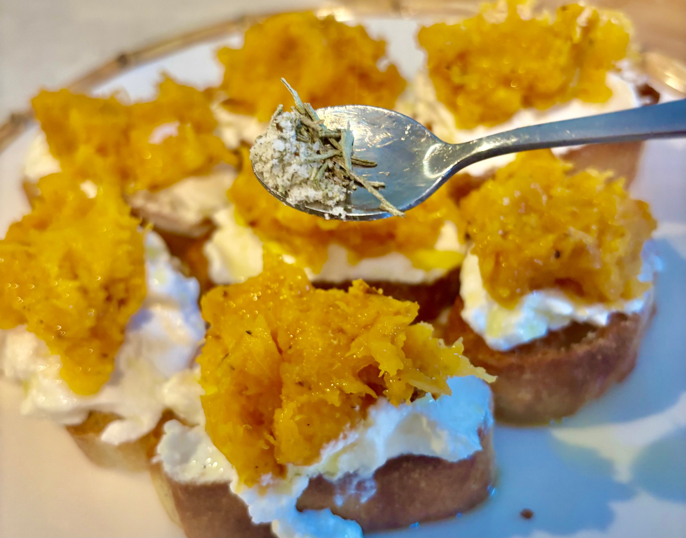Autumn bruschetta topped with ricotta and roasted butternut squash with rosemary salt being sprinkled