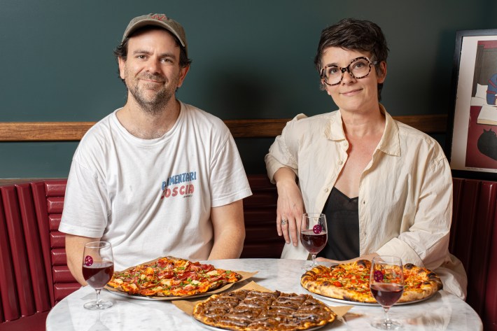 Mike Fadem and Marie Tribouilloy seated at Ops East Village with pizzas and red wine.