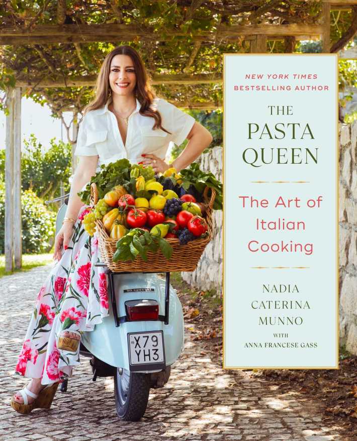 Nadia Caterina Munno poses on a Vespa with a basket of colorful vegetables for her cookbook “The Pasta Queen: The Art of Italian Cooking.