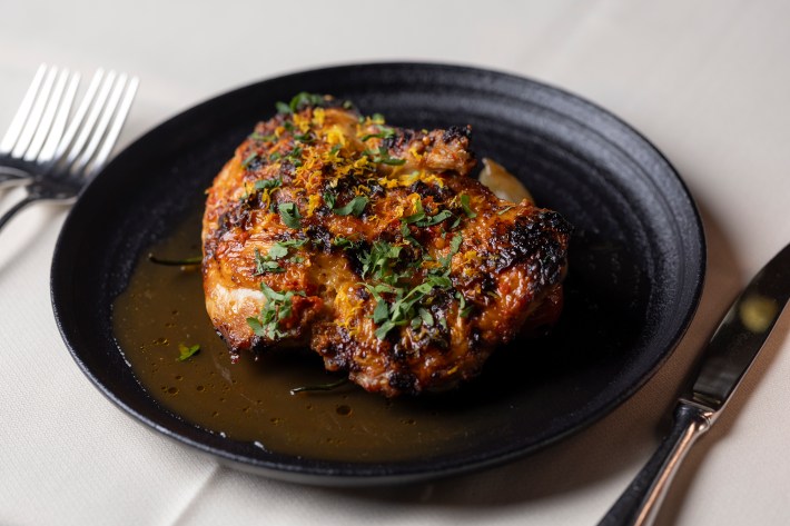 Pollo alla Diavola chicken with orange and Calabrian chili on a black plate at Bottega Napa Valley.