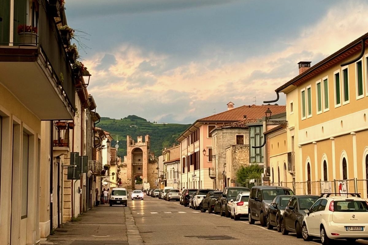 Street view of Soave with pastel buildings and the ancient town gate framed by vineyard hills.