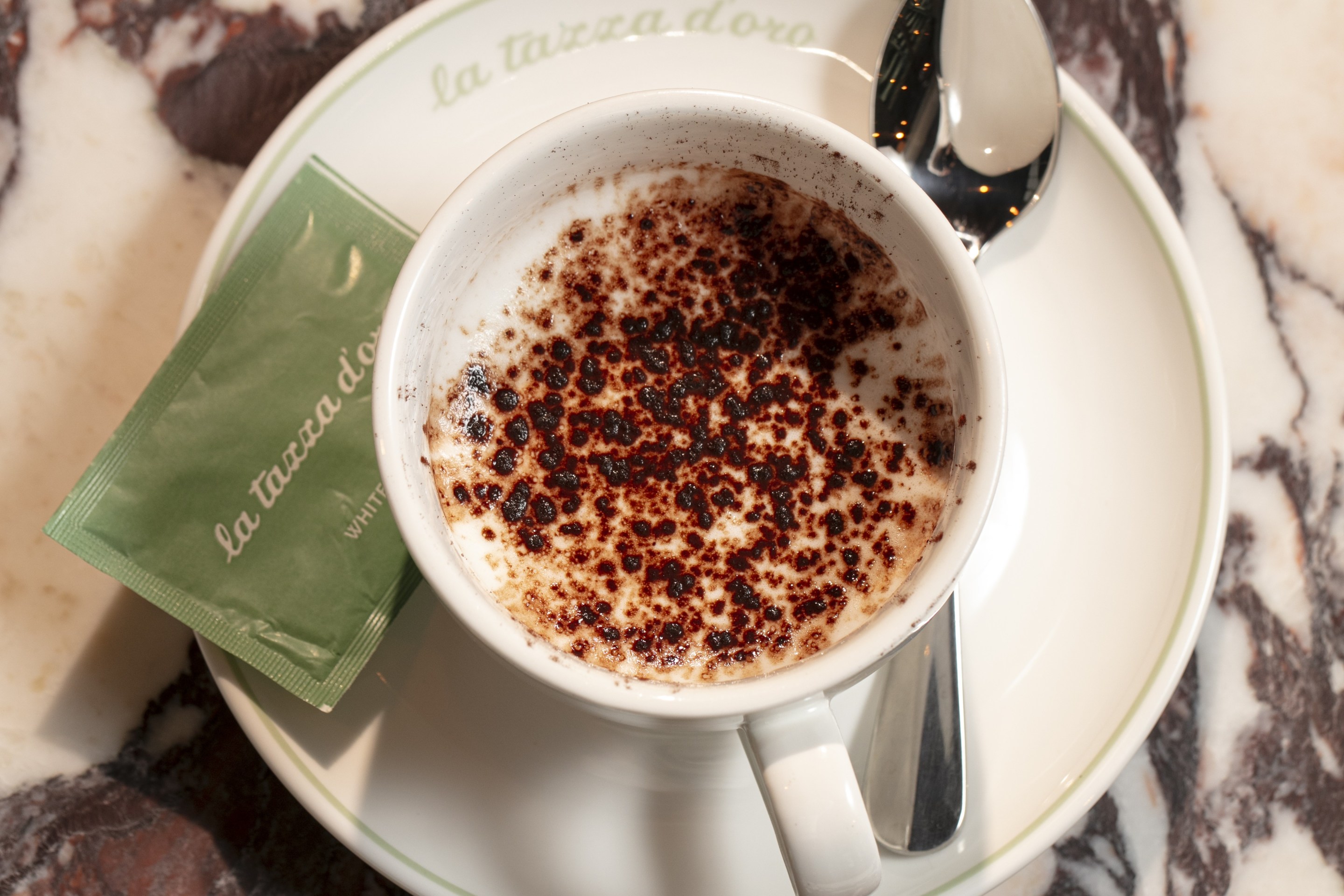 Capolavoro espresso macchiato with cocoa on marble table