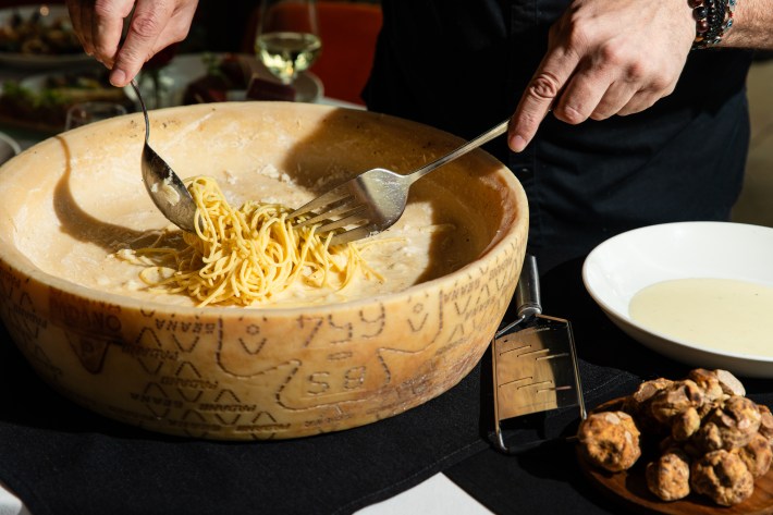Chef preparing truffle pasta inside a parmigiano reggiano cheese wheel. Photo by Becca Wright.