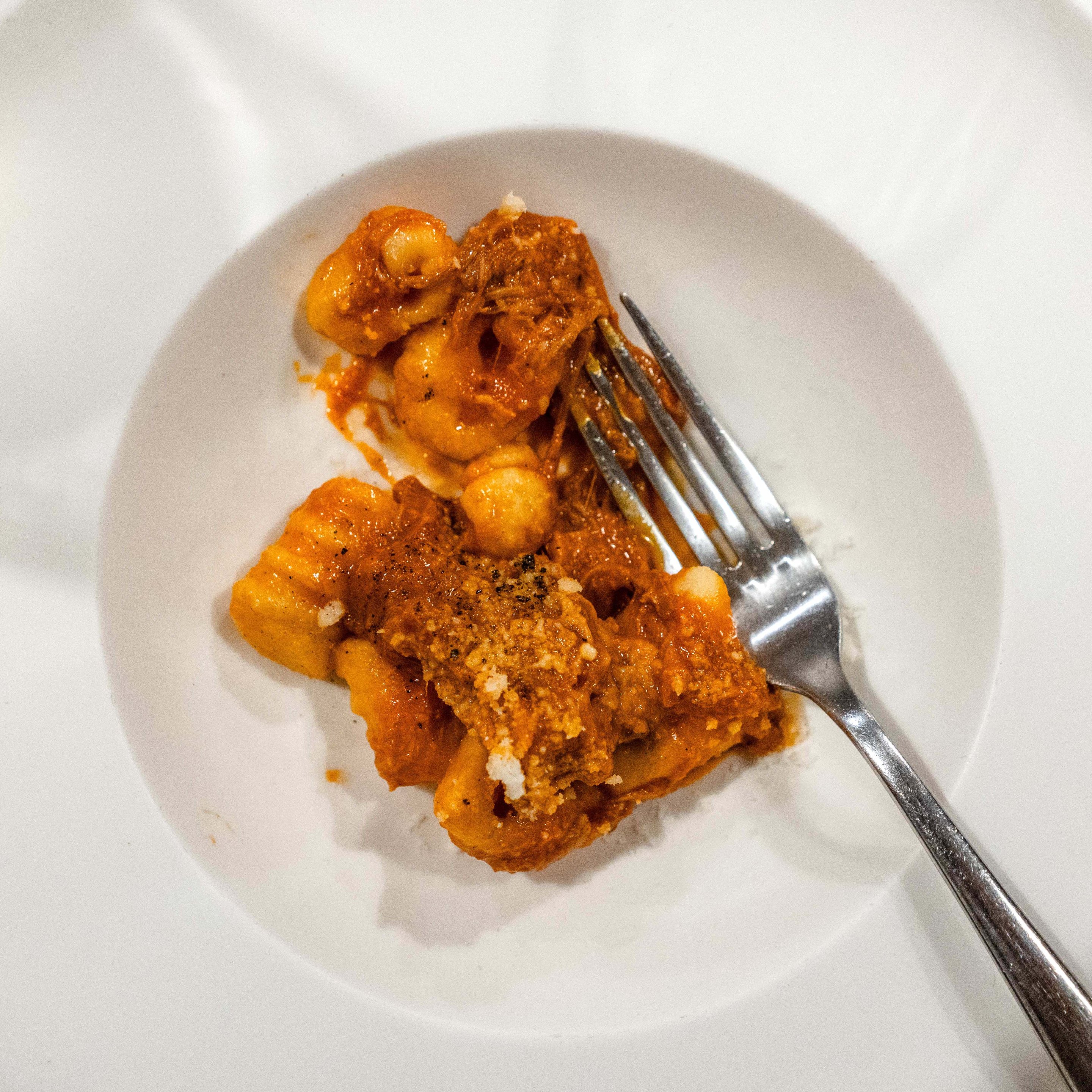 Gnocchi served with slow-cooked ragù on a white plate.