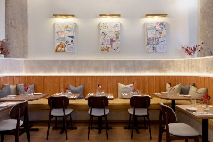 Interior of Ziggy’s Roman Cafe showing wood banquettes, kids artwork, and soft neutral lighting.