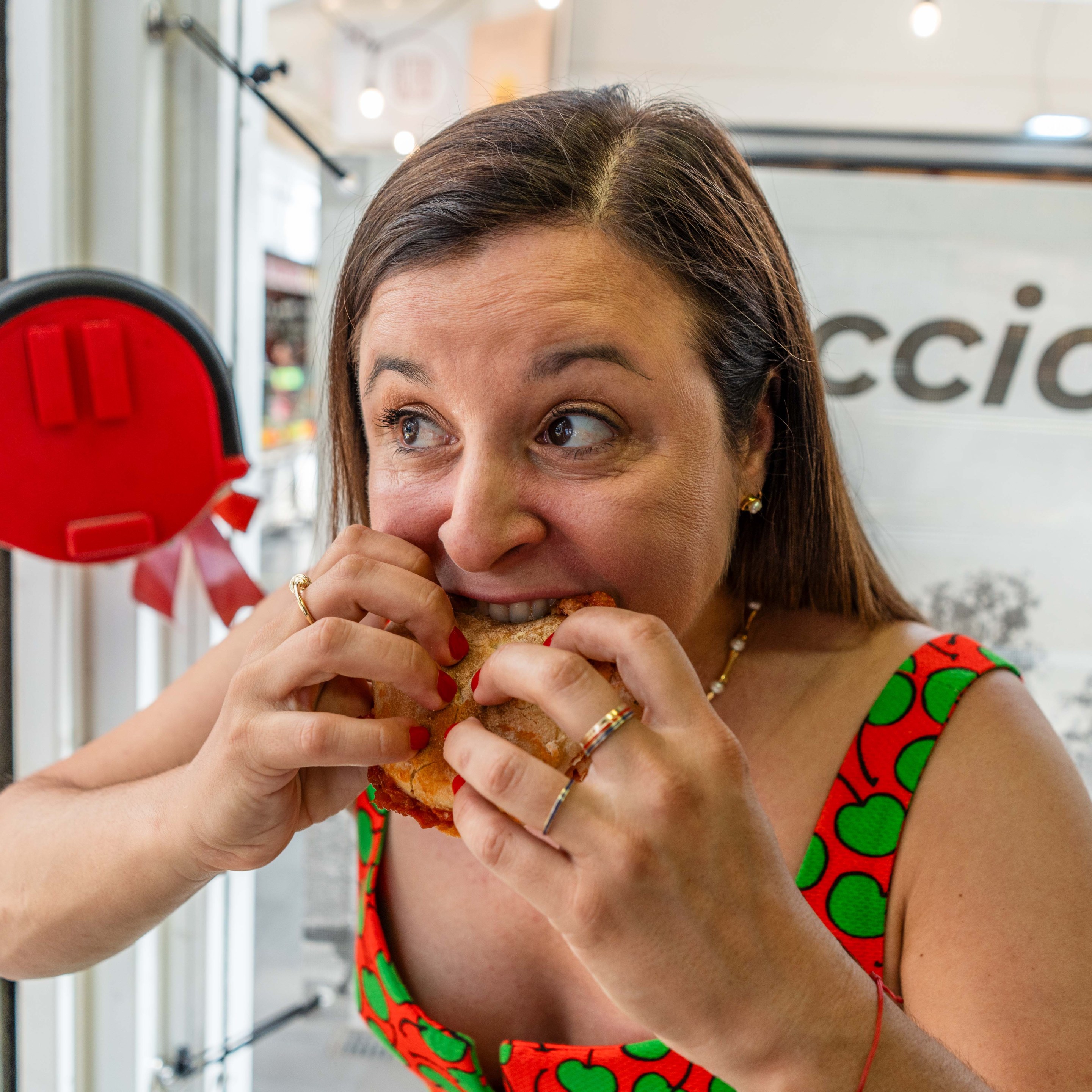 Katie Parla taking a big bite of a Roman sandwich inside a local shop.