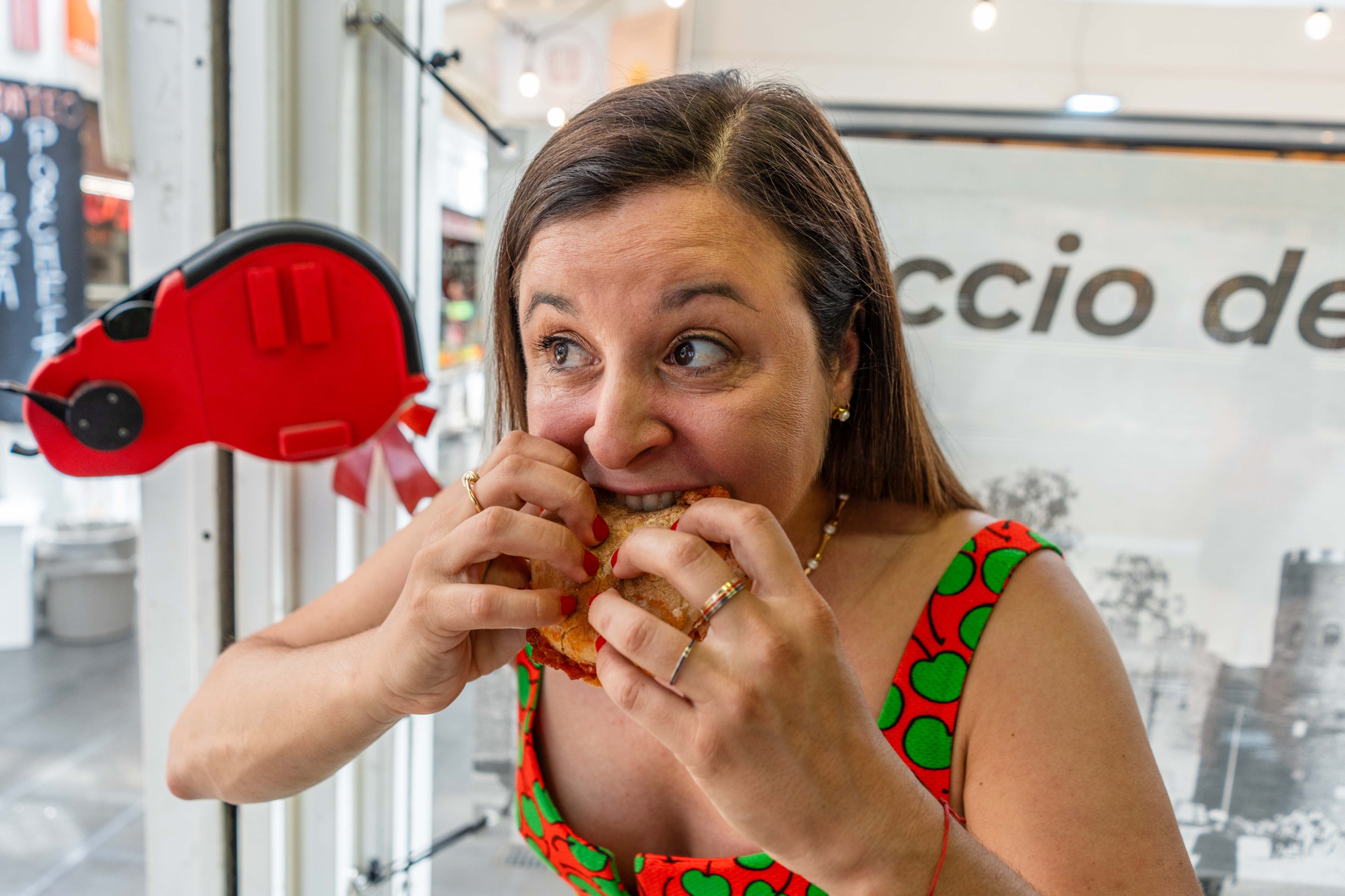 Katie Parla taking a big bite of a Roman sandwich inside a local shop.