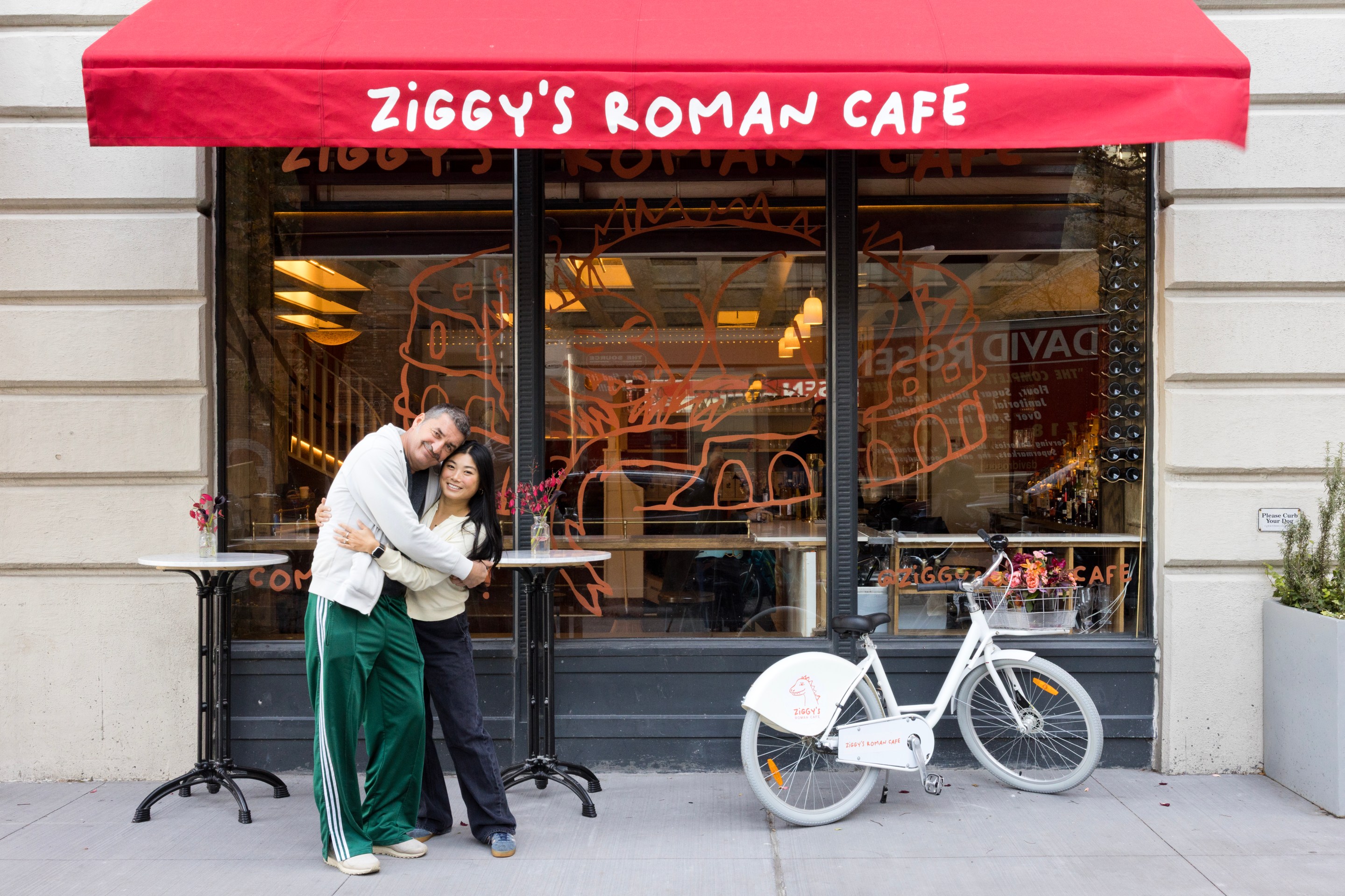 Helen Zhang and Igor Hadzismajlovic standing together under the red Ziggy’s Roman Cafe awning.