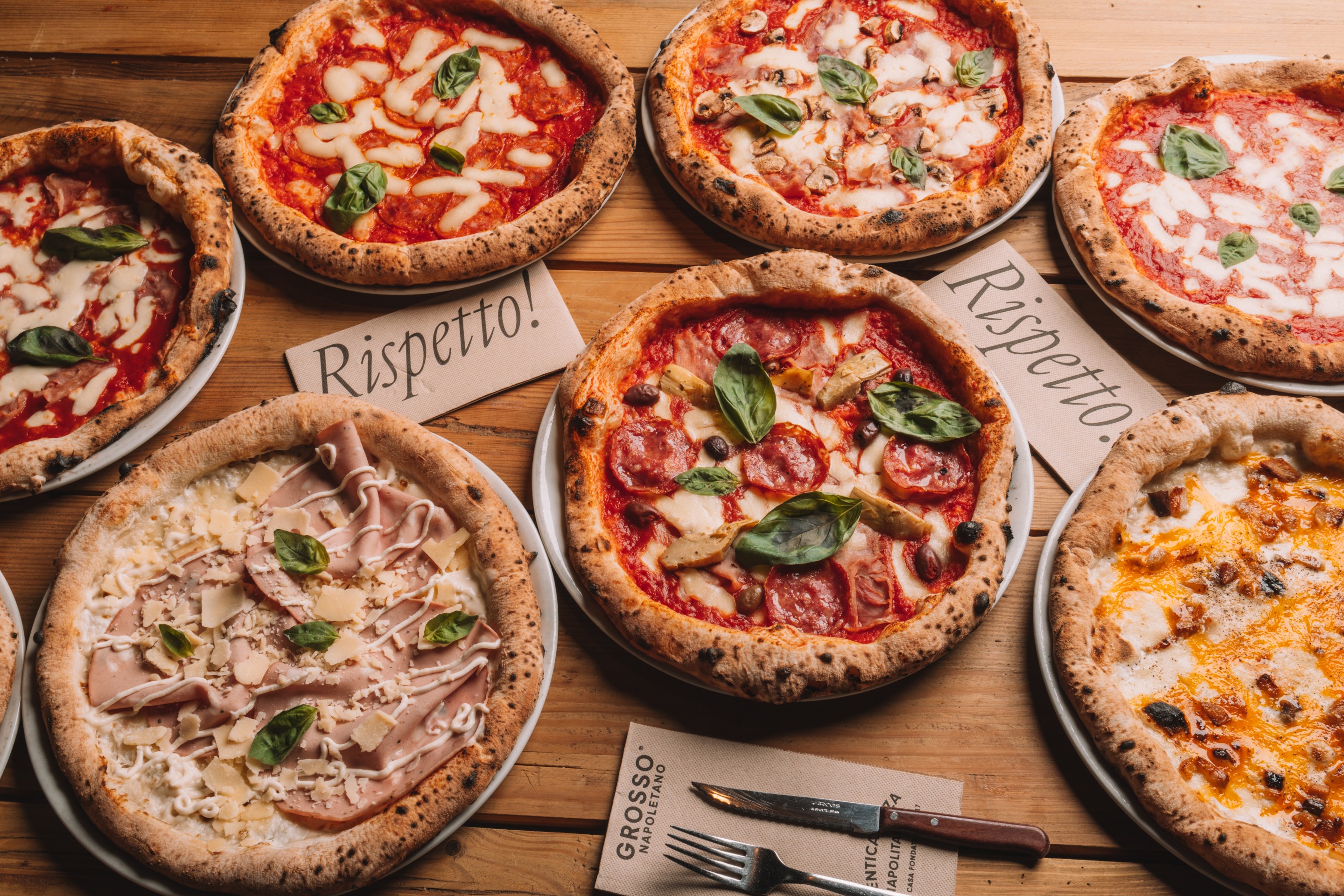 Various pizzas arranged on a wooden table at Grosso Napoletano.