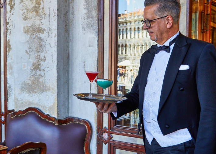 Bartender in formal attire serving cocktails at Caffè Florian in Venice.