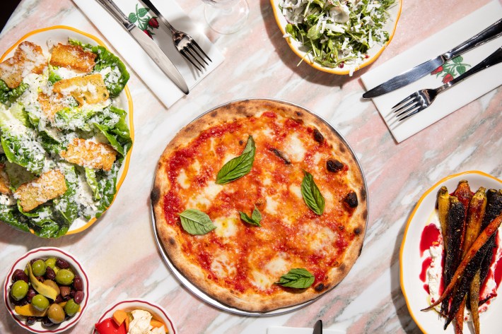 Overhead shot of a pizza and vegetable sides at Ziggy’s Roman Cafe.