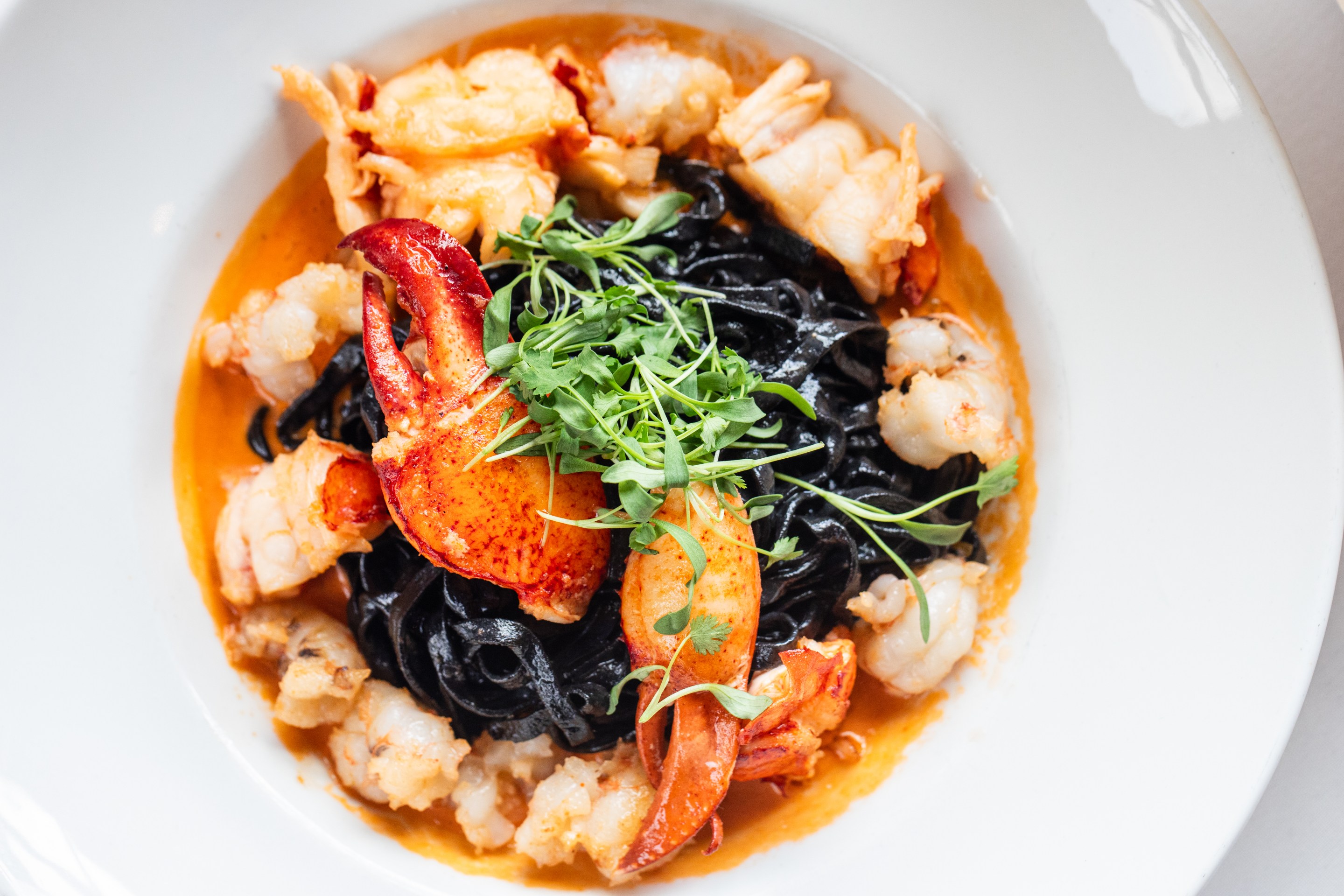 Squid ink pasta topped with fresh lobster and herbs in a tomato based sauce. Photo by Becca Wright.