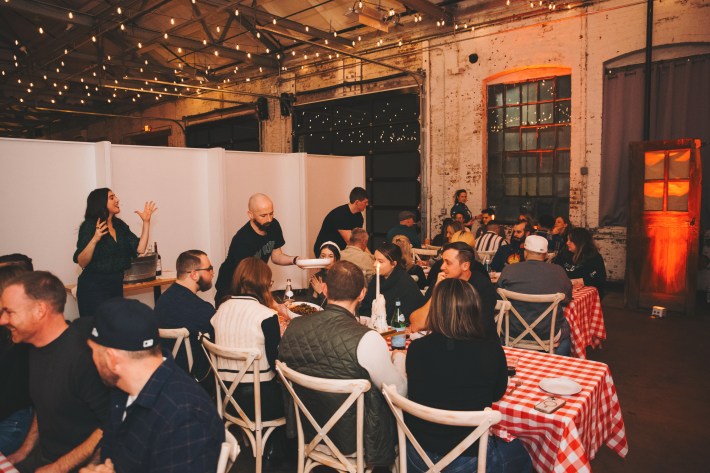 Guests seated at long tables enjoying a family-style Italian dinner at Midnight Pasta in Philadelphia.