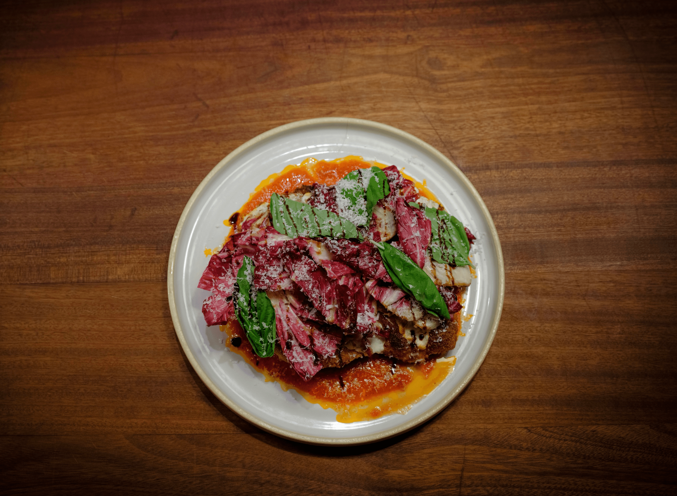 Plated chicken parm on a wooden table, from Chef Georis from Maligne's.