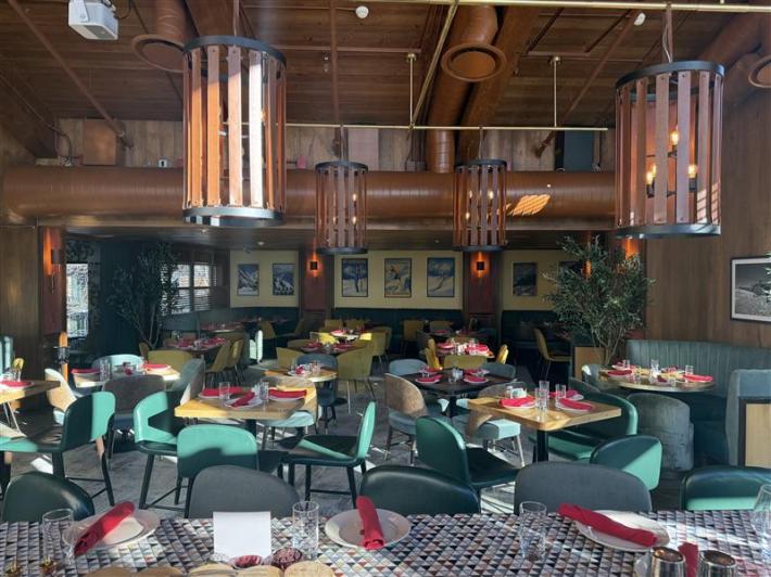 Mt. Rubirosa dining room with wood ceiling, large lantern lights, and green chairs around set tables.