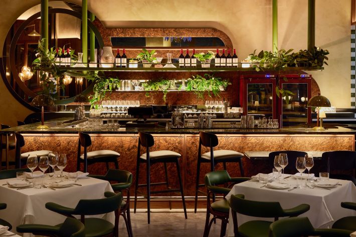 Interior bar at Ezio’s in Miami Beach with greenery, guests dining, and an intimate steakhouse setting