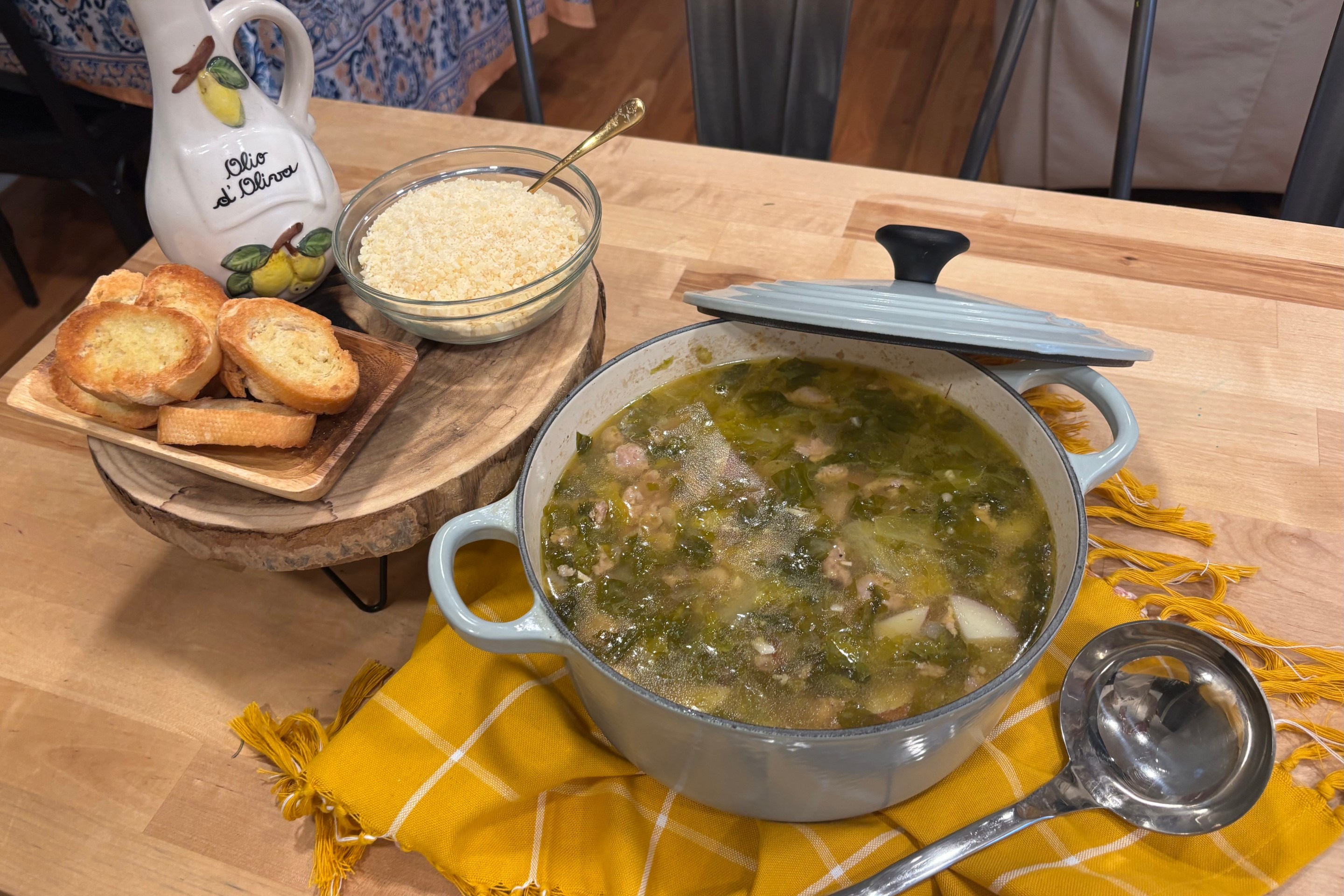 Dutch oven filled with Italian sausage soup with escarole, potatoes, and cannellini beans