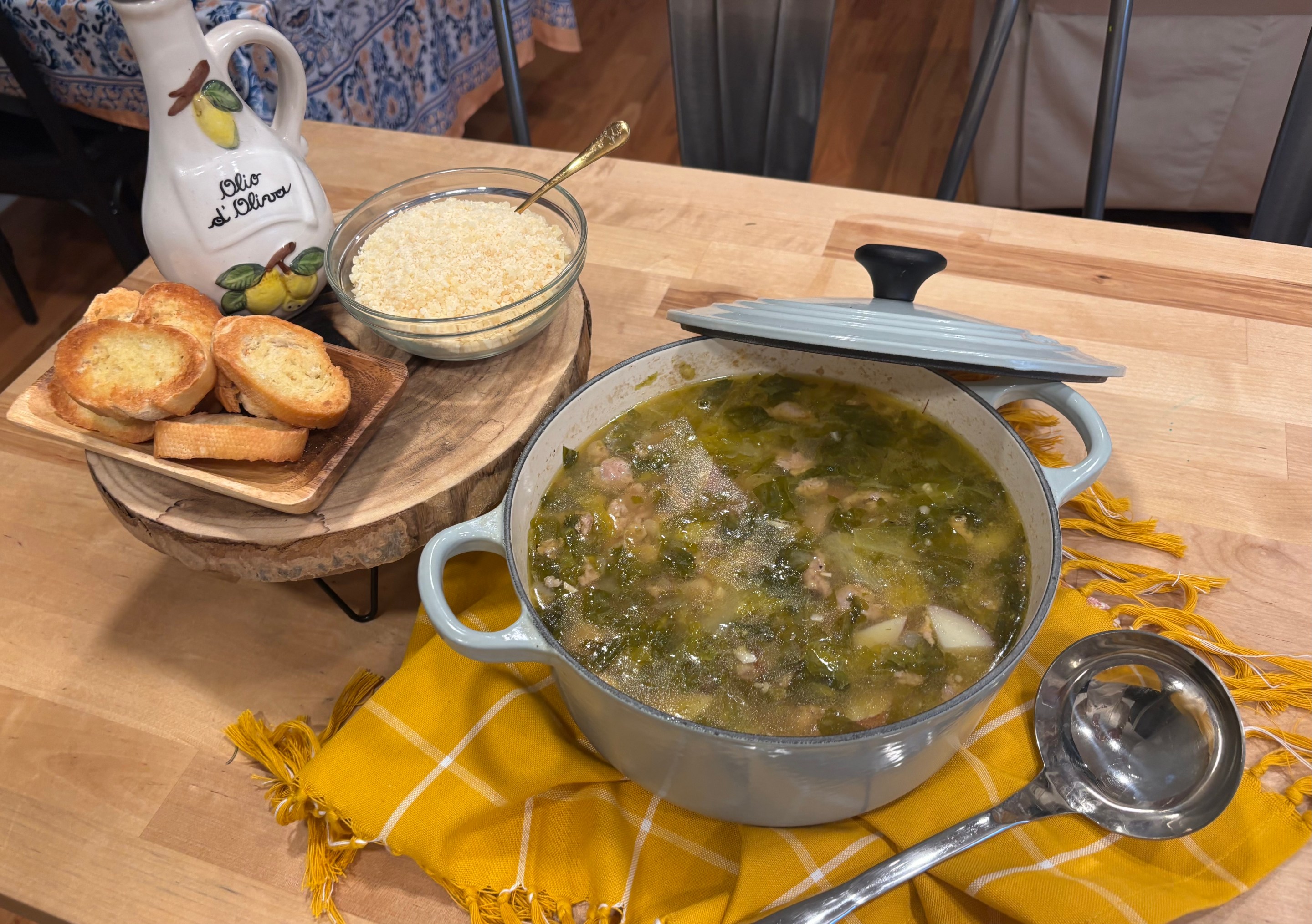 Dutch oven filled with Italian sausage soup with escarole, potatoes, and cannellini beans