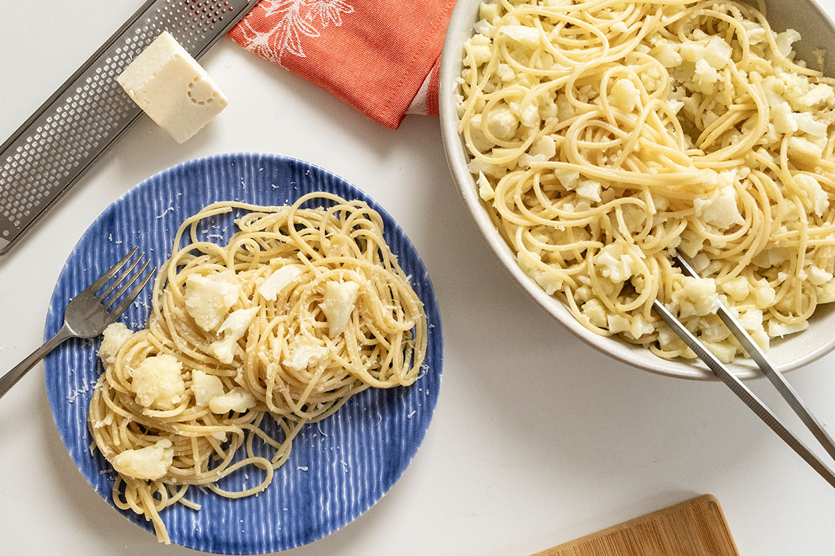 Bowl and plate of pasta with cauliflower topped with pecorino romano