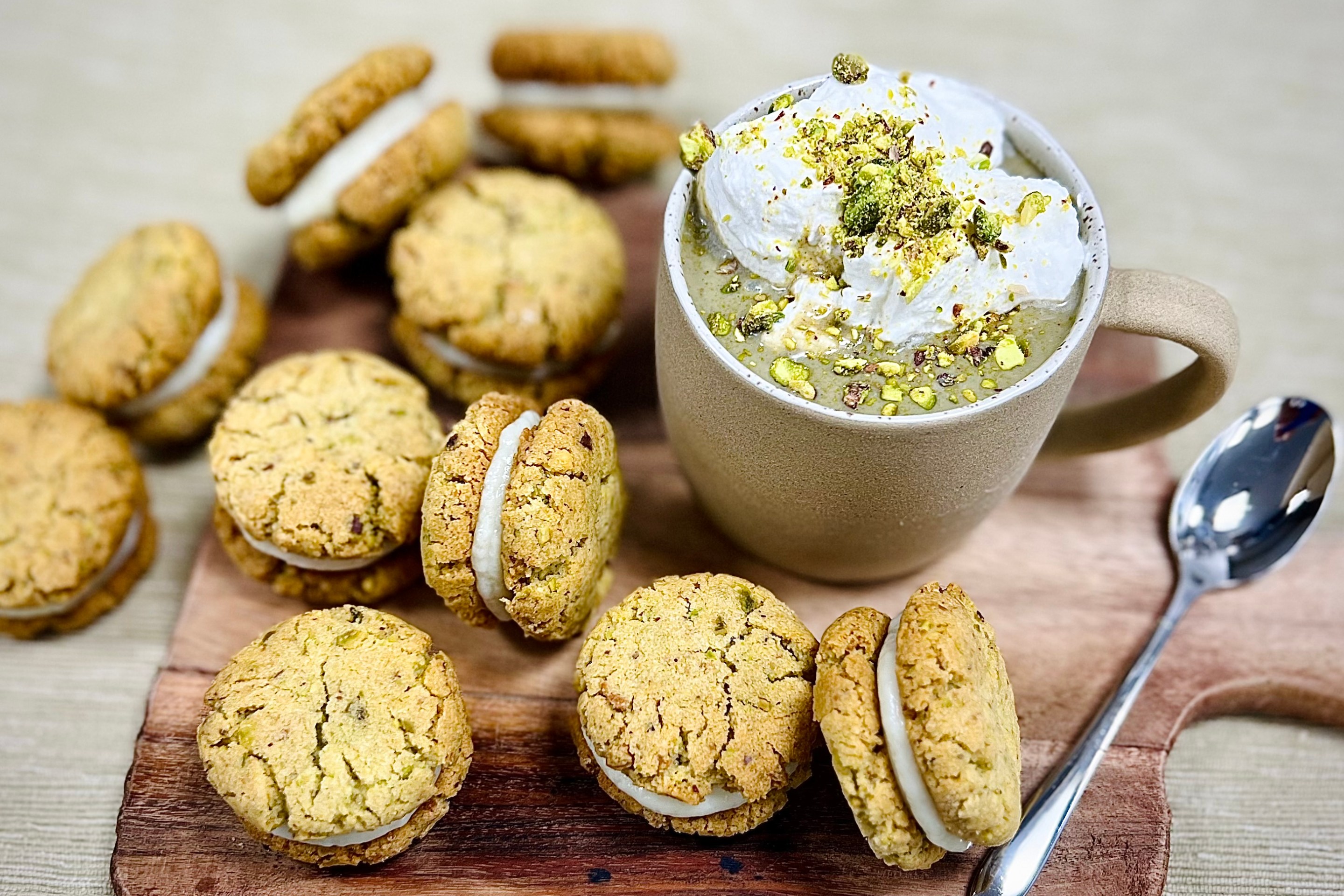 Pistachio hot chocolate with whipped cream and chopped pistachios served with pistachio cookies filled with white chocolate ganache.