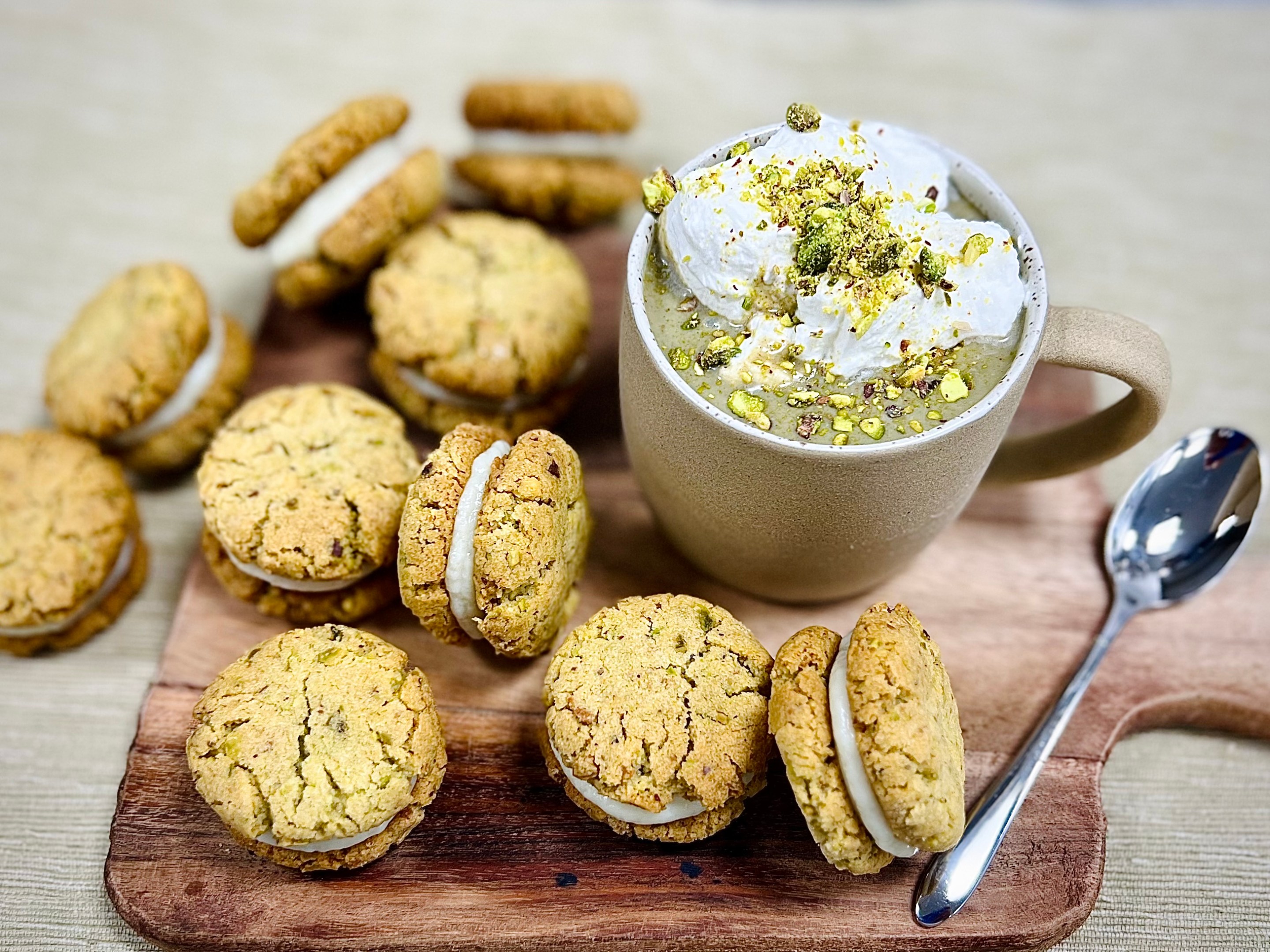 Pistachio hot chocolate with whipped cream and chopped pistachios served with pistachio cookies filled with white chocolate ganache.