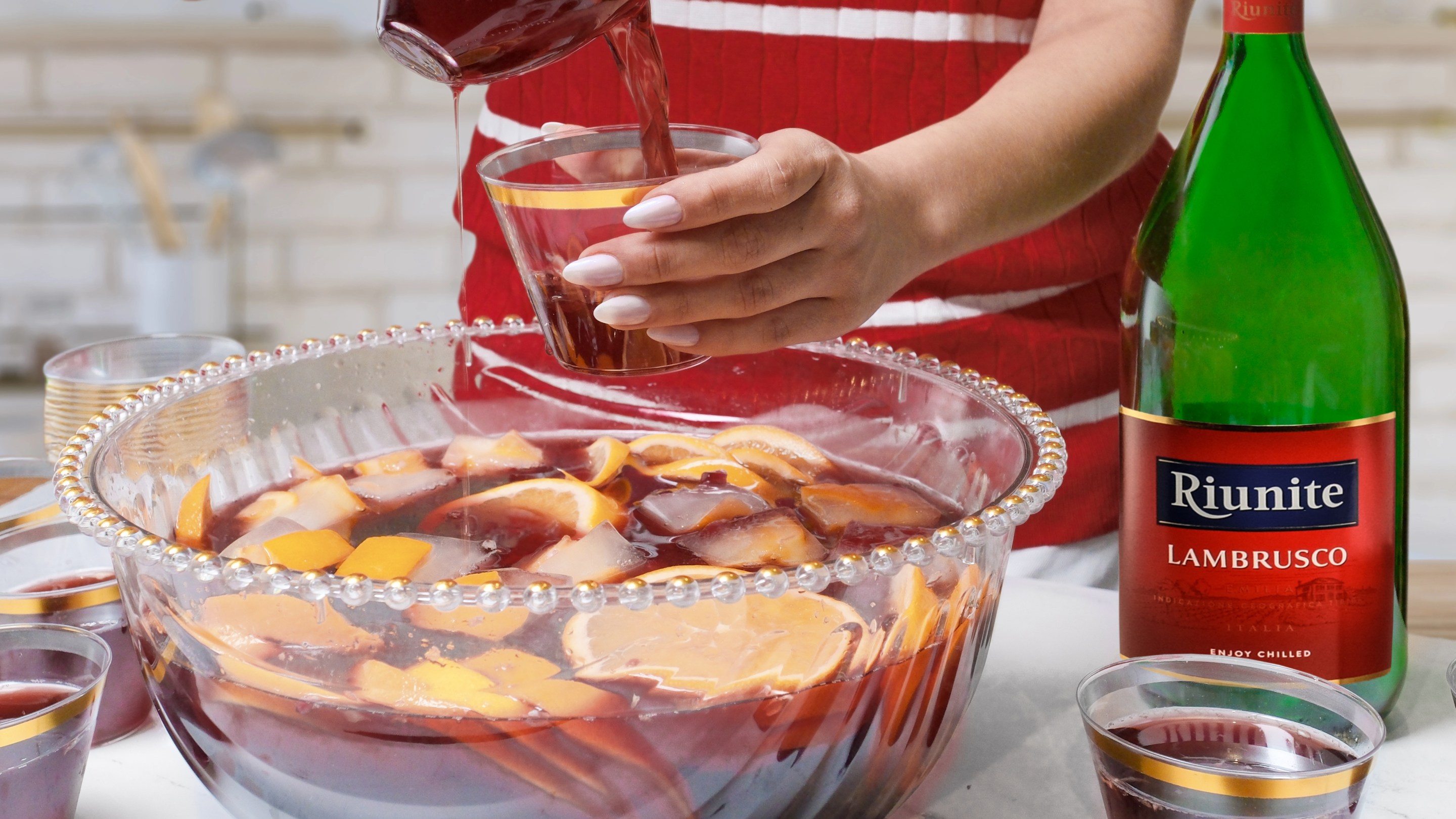Lambrusco Punch made with chilled Riunite Lambrusco, pomegranate juice, citrus, and frozen fruit cubes brings a festive Italian twist to Super Bowl Sunday entertaining.